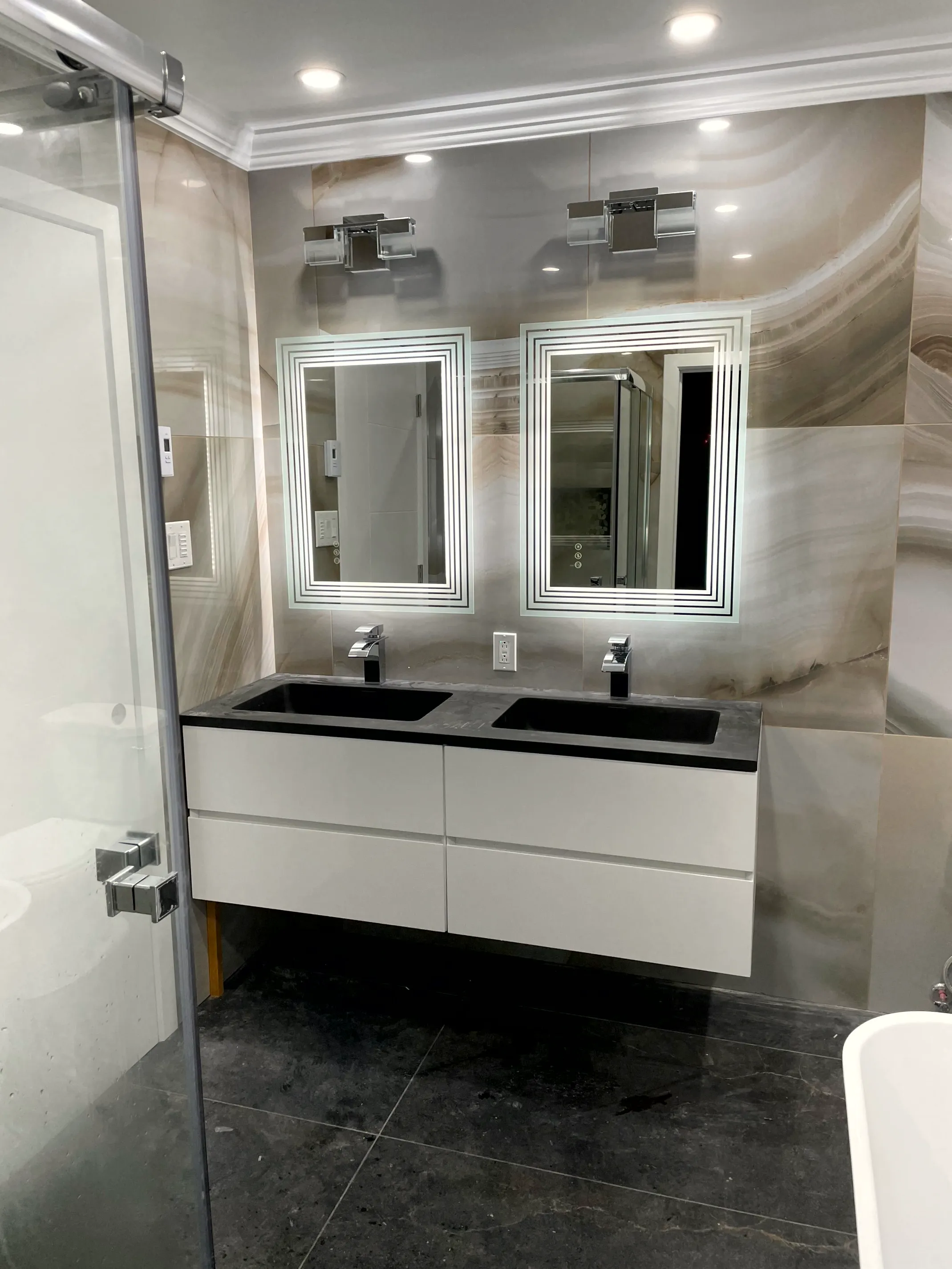 Finished double-vanity bathroom with LED mirrors and marble tile by ToughJobs
