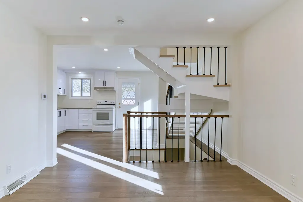 Finished open-concept main floor with a modern open staircase, iron balusters, white-oak flooring, and a bright renovated kitchen.