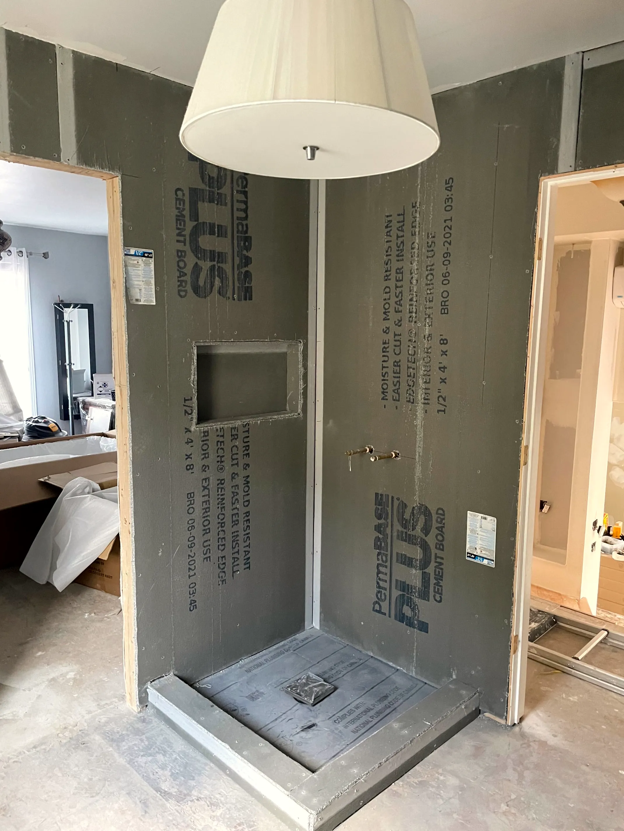 Corner shower stall in cement board with a niche, valve set, and shower base in place.