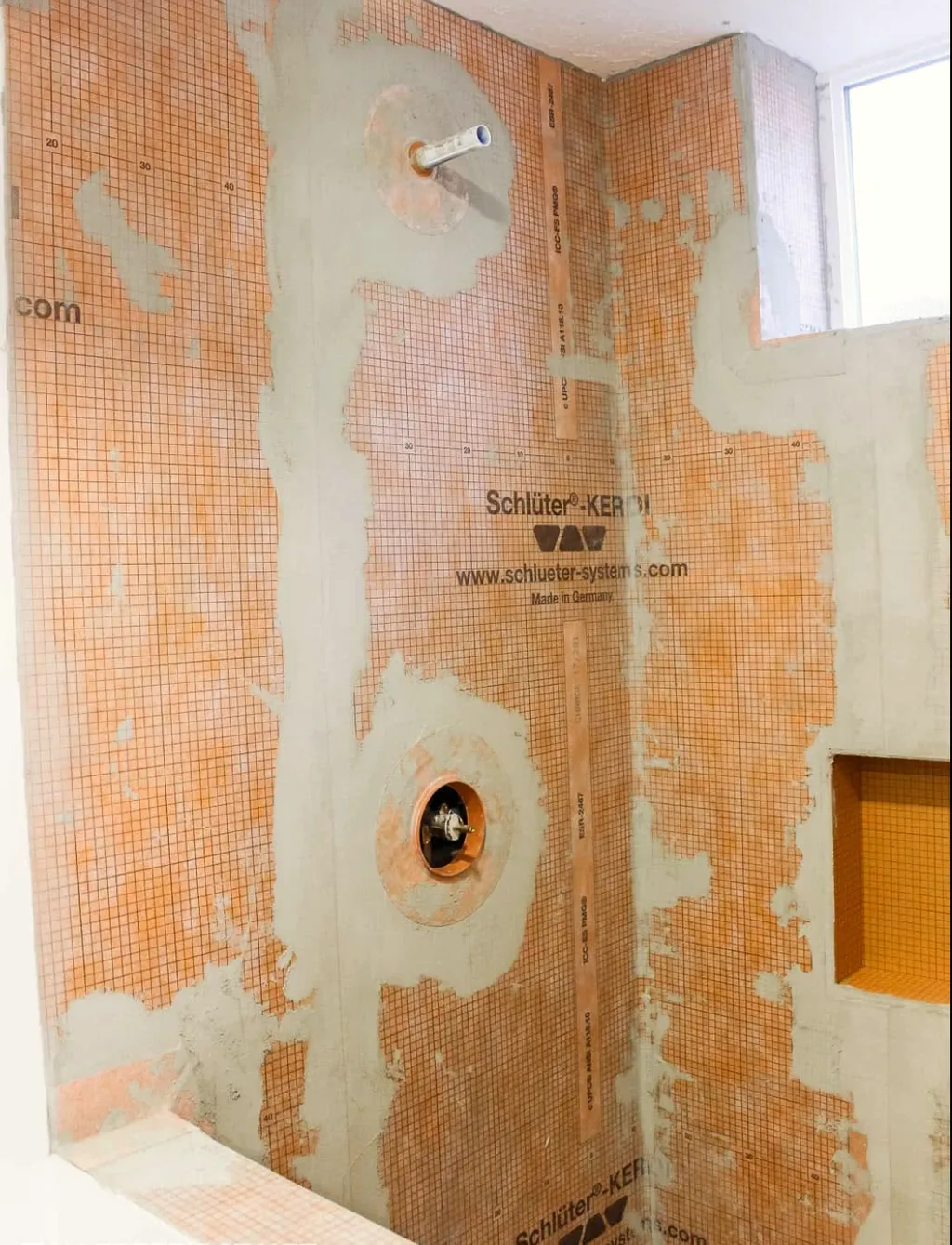 Shower walls clad in a waterproofing membrane, with the mixing valve and head outlet set in the wall.