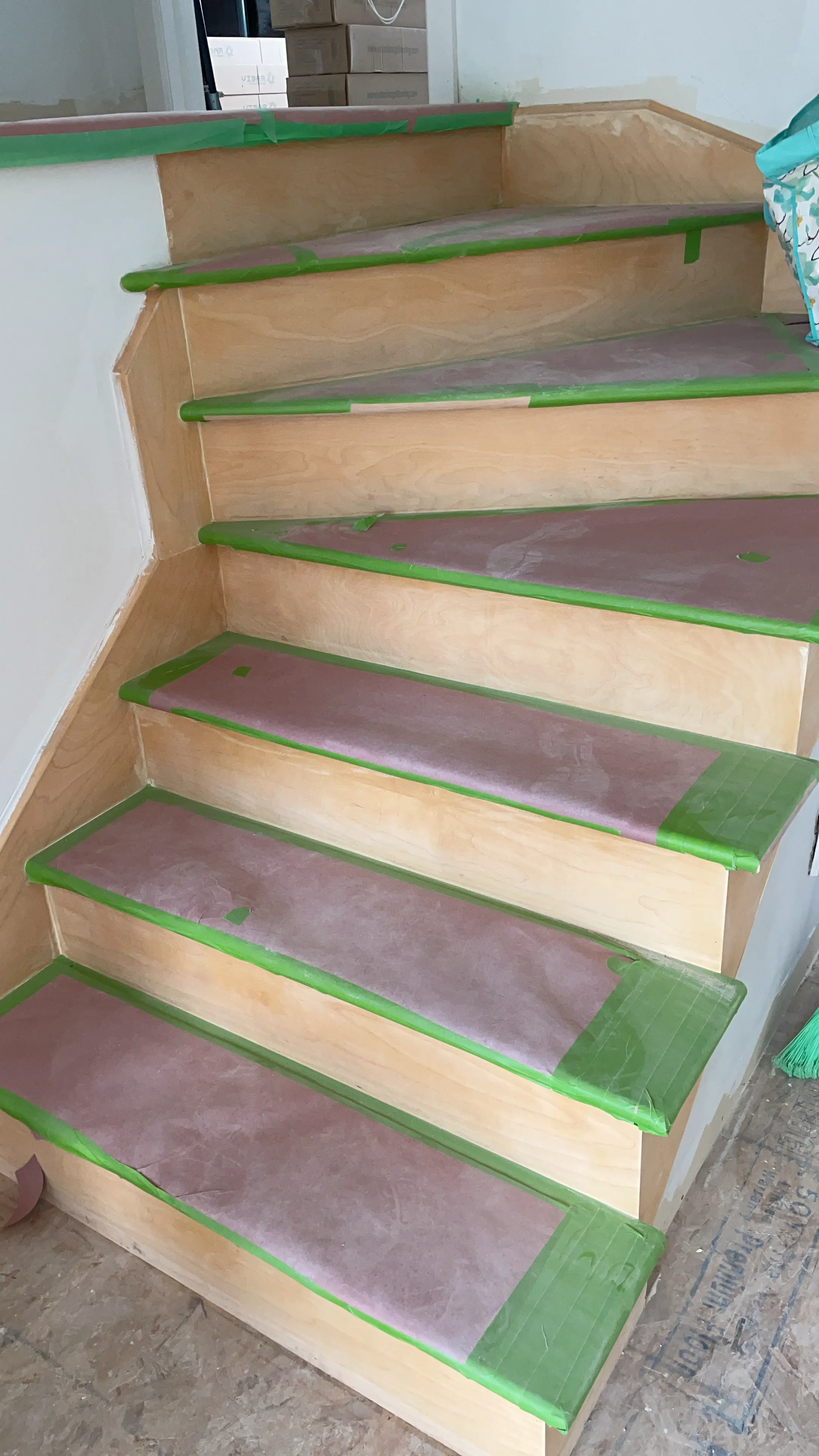 New wood stair treads covered with paper and tape, set on wide wood stringers.
